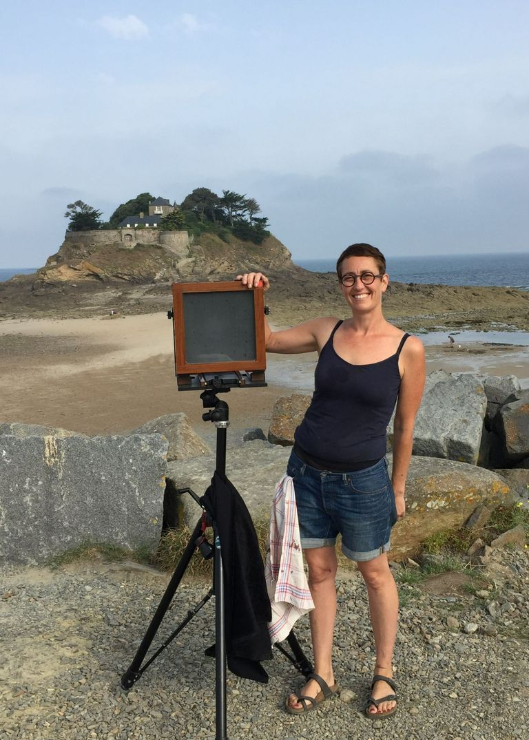Fotógrafa posando con su cámara de colodión cerca del mar en Bretaña, Francia