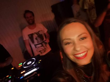 DJ sonriendo de fondo y chica sonriendo en primer plano