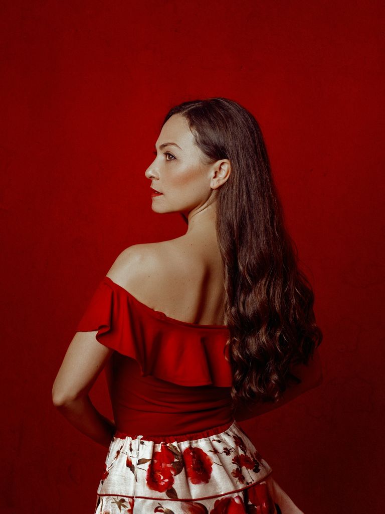Mujer con pelo largo en fondo rojo y mirada firme