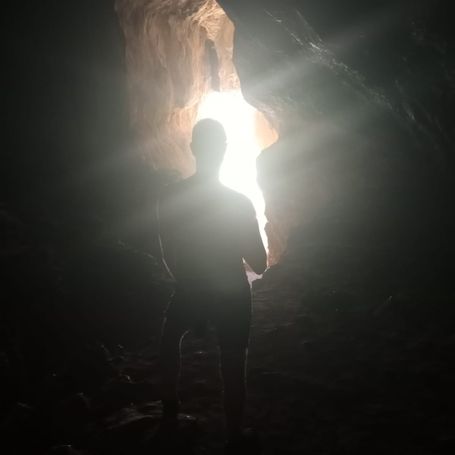 Chamán a contraluz dentro de la montaña viendo la luz