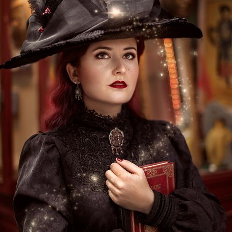 Mujer vestida de época con vestido negro y un libro en la mano